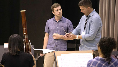 Professor demonstrating proper conducting technique to a graduate student.