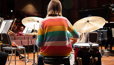 Jazz student sitting on stage behind a drum kit.