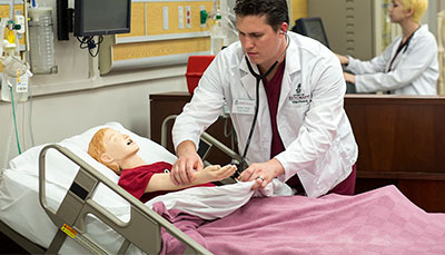Nursing student working with an adolescent healthcare simulation mannequin. 