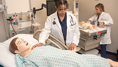 Two student practicing on nursing mannequins in a simulation lab