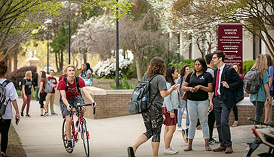 Large collection of students on walkway near campus science building.