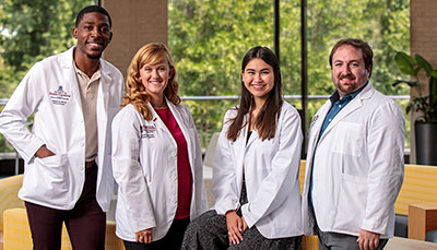 Four medical students standing together in a lab coats. 