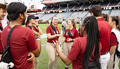 Group of students standing on the sidelines of the football field of Williams-Brice Stadium.