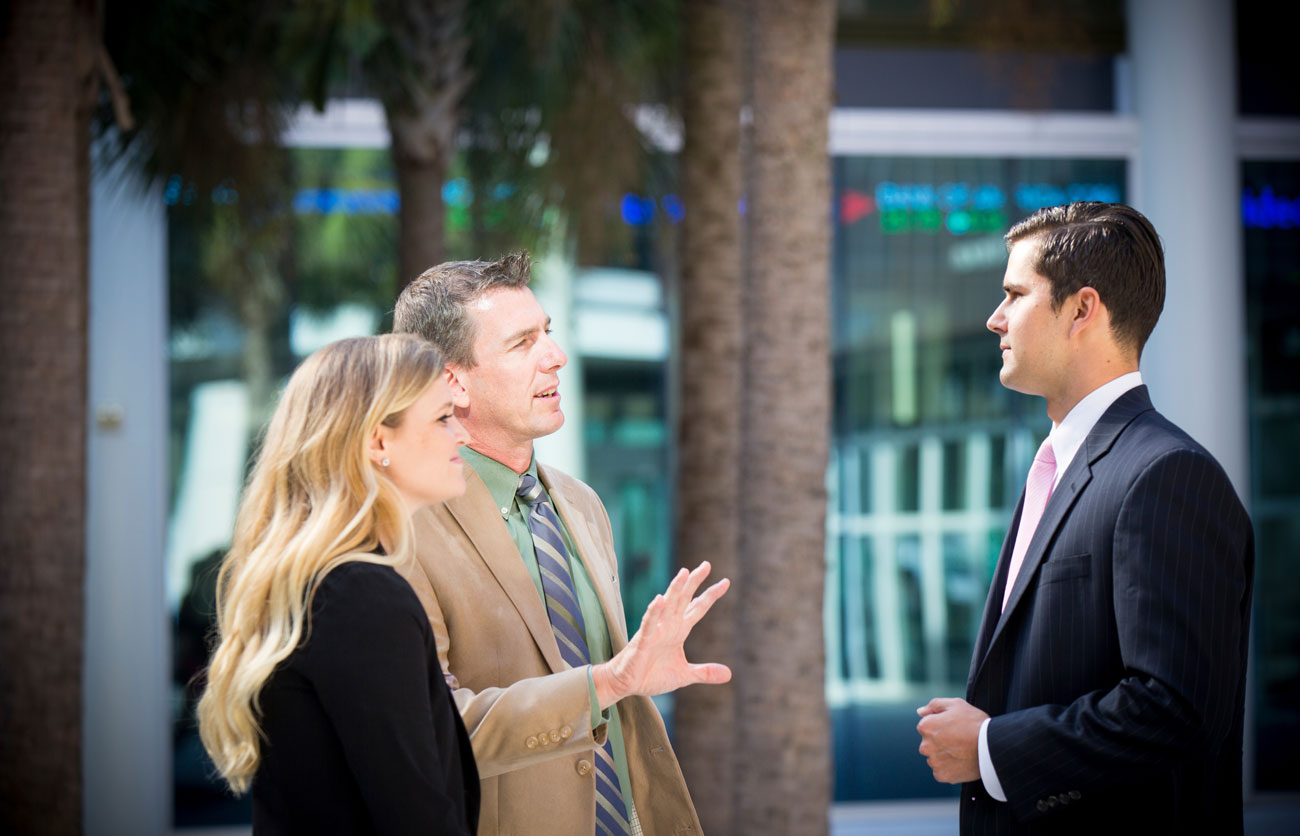 Three business professionals speaking outside of the Moore School.