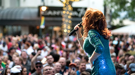Person on stage singing into a microphone with a view of the crowd over their shoulder. 