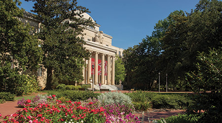 McKissick Museum surrounded by lush trees and flowers on a beautiful sunny day.