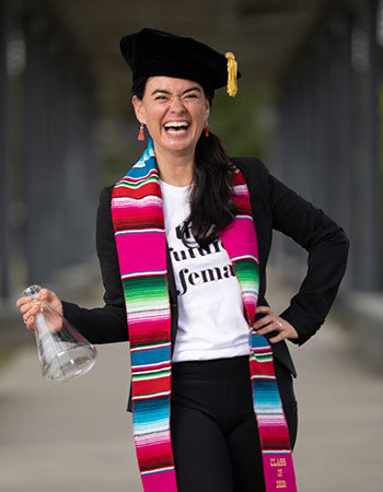 Portrait of Diana Lockwood wearing graduation cap and robes holding a beaker. 