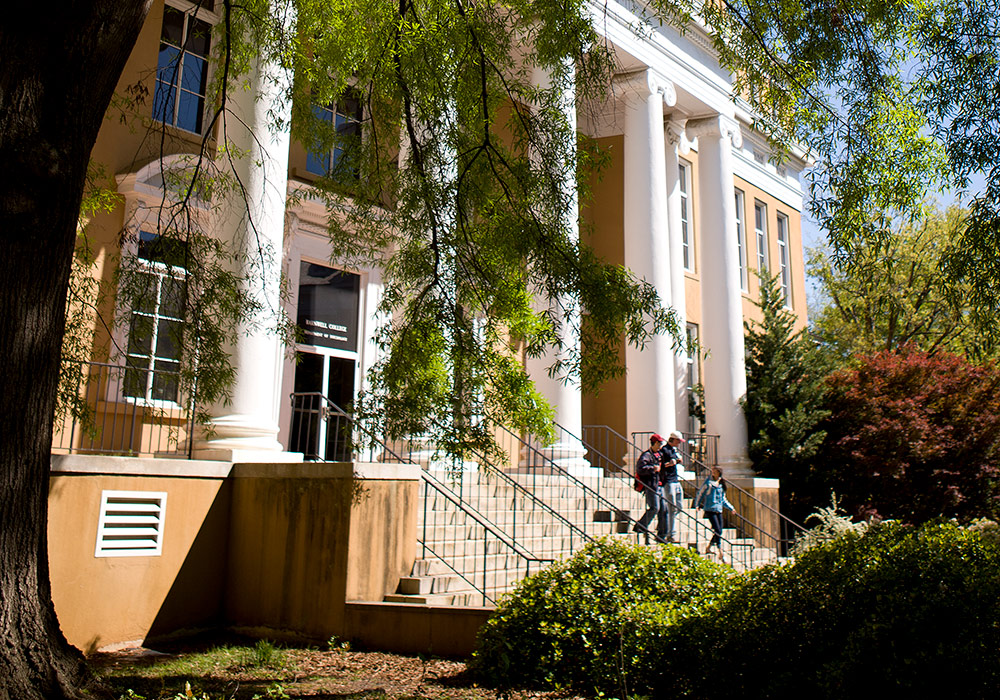 Large white columns adorn the front of Barnwell College with a few students walking down the steps. 