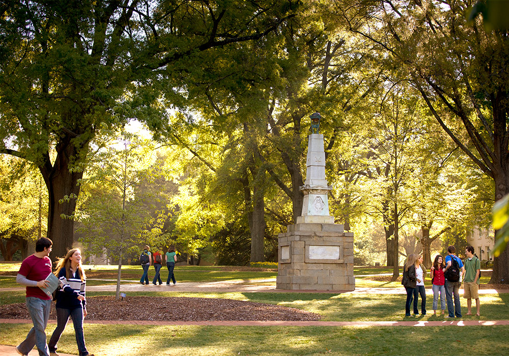 Several groups of students walking on the brick paths of the historic horseshoe with the Maxcy monument in the center of it. 