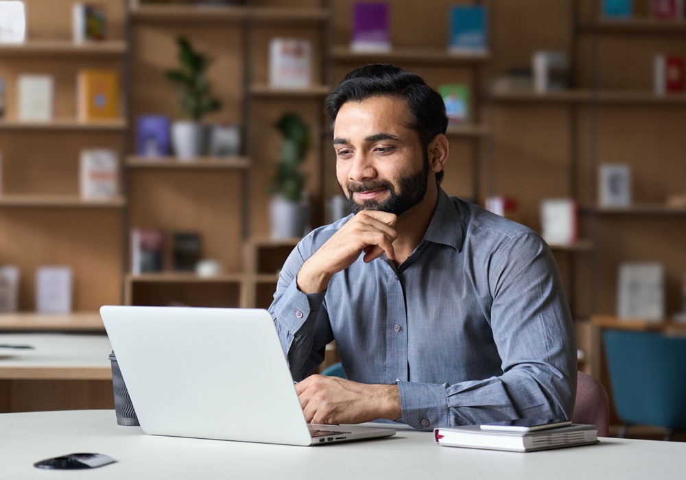 Young professional at a desk working on a laptop.