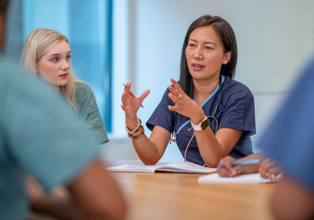A nursing instructor teaching students in a group setting at a table