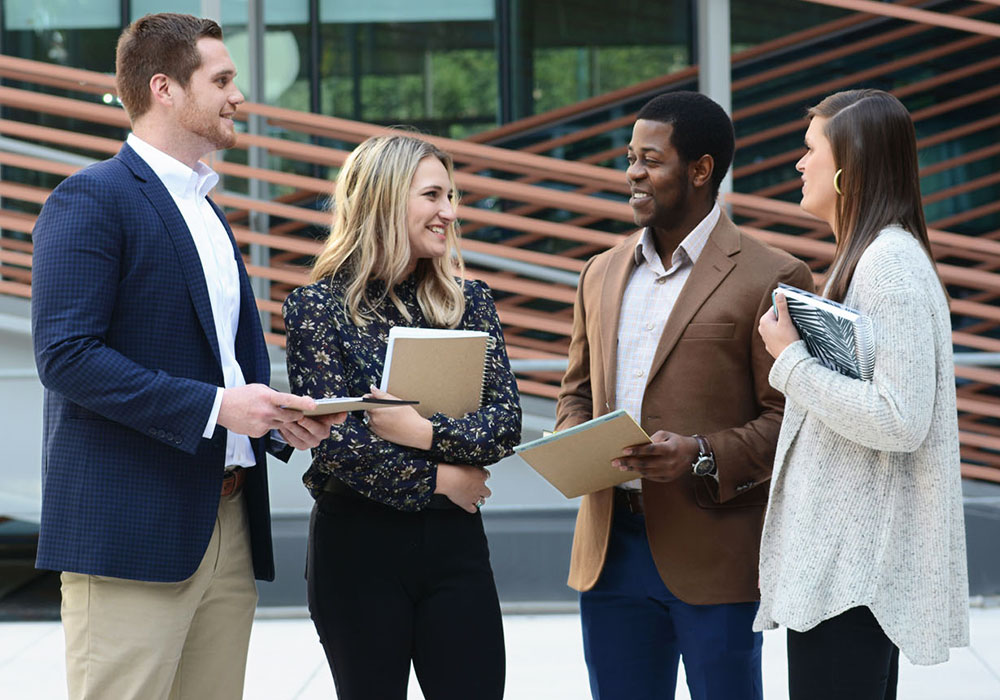 A group of students with notebooks speaking to each other