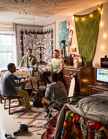 Three students hanging out in resident hall room. 