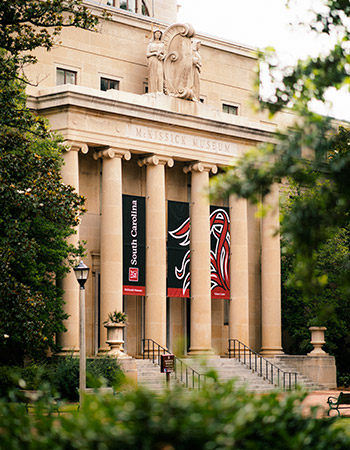 The front of McKissick Museum with large banners with the University of South Carolina logo and tailfeathers.