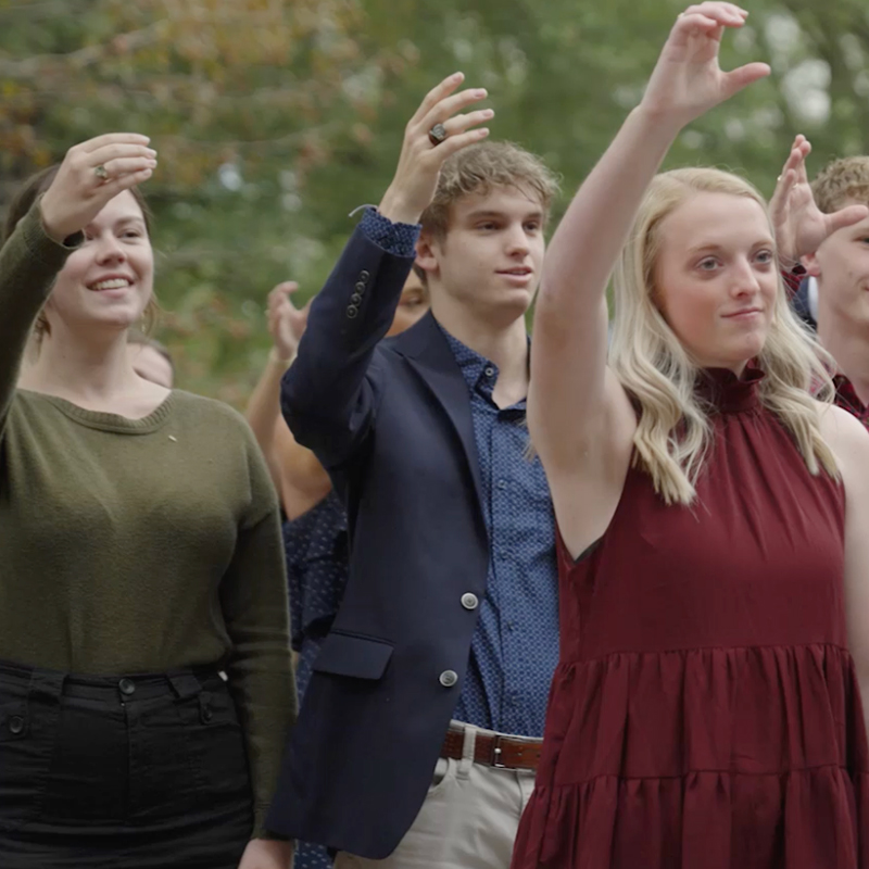 Alumni holding their hands up in the Here's a Health Carolina toast.