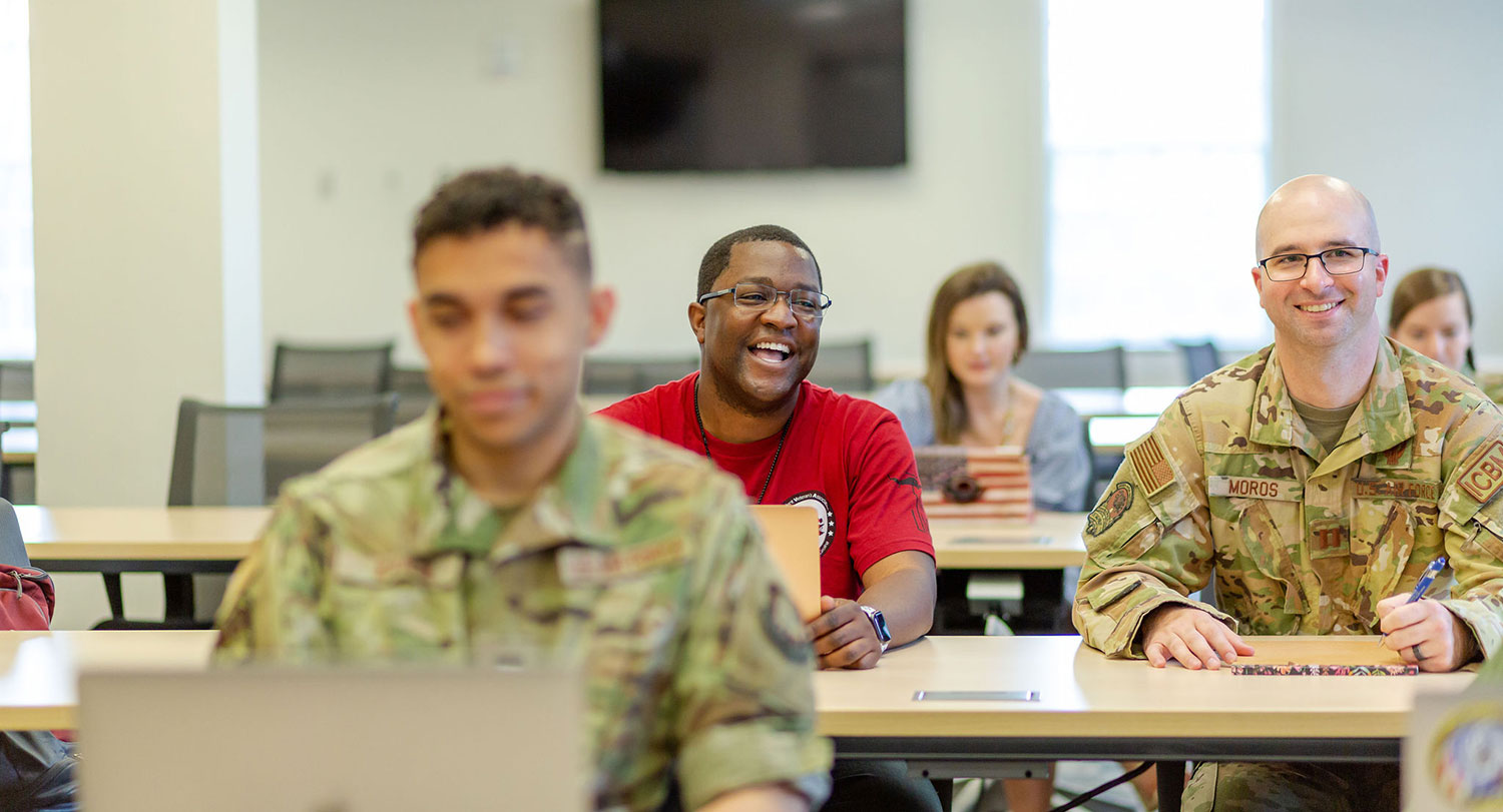 A veteran student and other ROTC students smiling in a classroom.