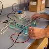 A students hands are pictured holding the wires of a piece of lab equipment.