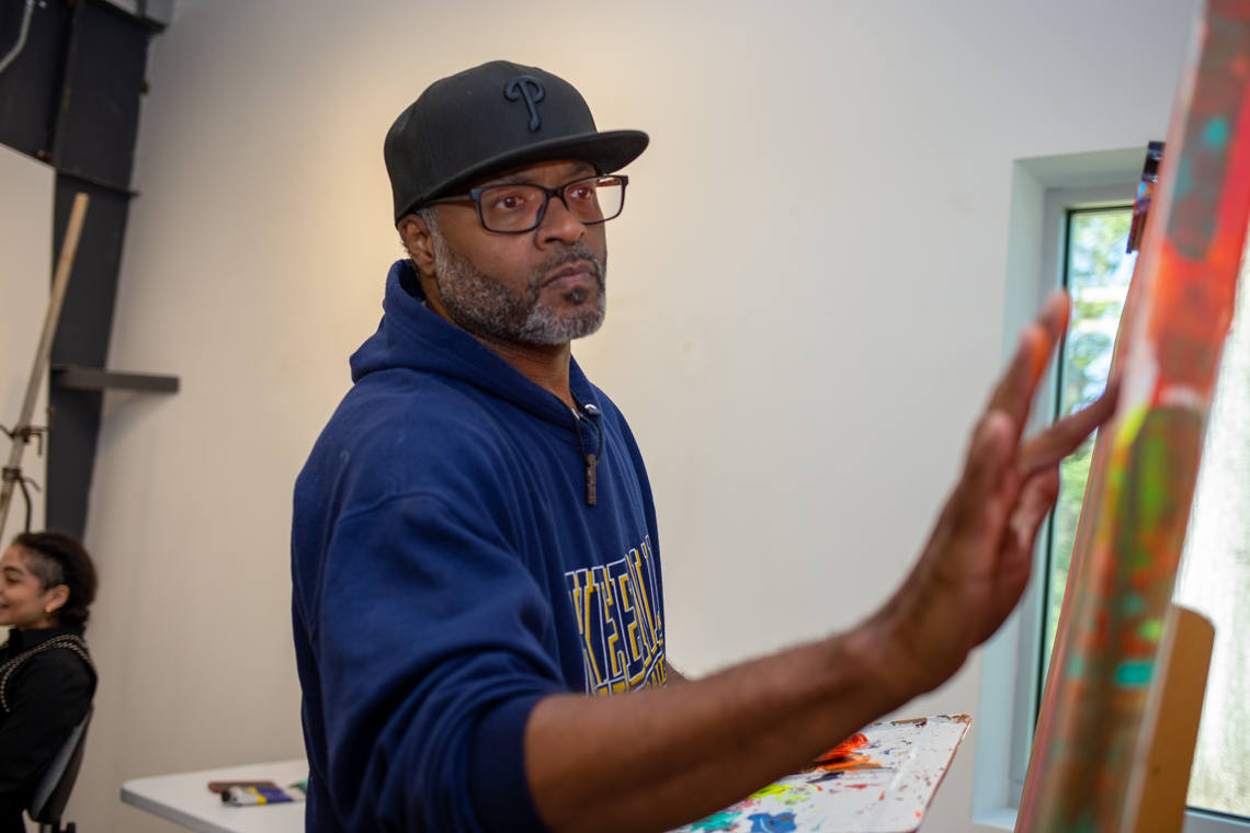 Anthony Lewis works on a large canvas painting.
