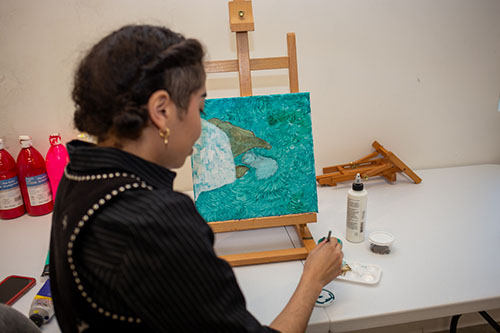 Ken Tips works on a small canvas painting.