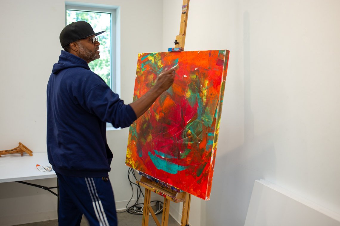 Anthony Lewis works on a large canvas painting. 