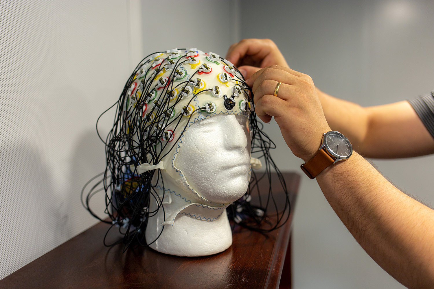 Nicholas Riccardi’s hands hold a cap with diodes used for brain stimulation.