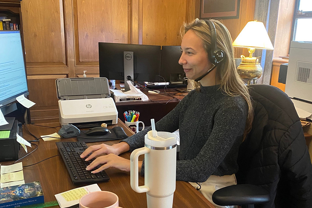 Kiley Cosby works at her desk with a headset on to take calls.