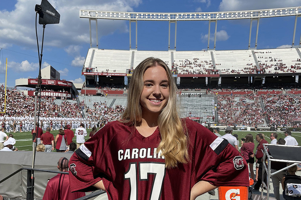 Katie McBride stands inside Williams-Brice Stadium with the crowd in the background.