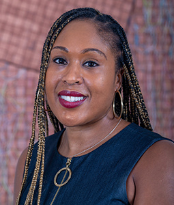 a woman in front a brick wall smiling 
