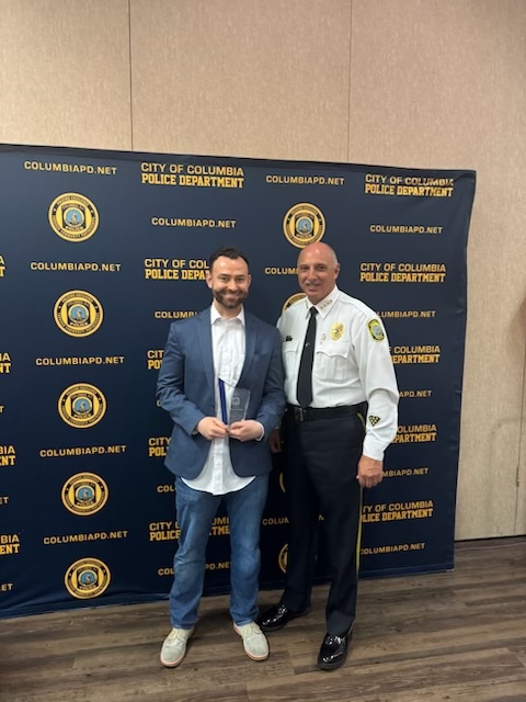 Assistant Professor Hunter Boehme receives the Outstanding Citizen Award from Columbia Police Chief Holbrook at an awards ceremony