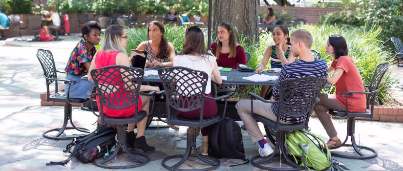 Students sitting at a table outside. 