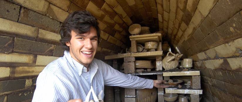 Student in a brick tunnel holding artifacts. 