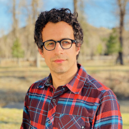 Portrait photo of Berns posing outside in a red flannel shirt and glasses.