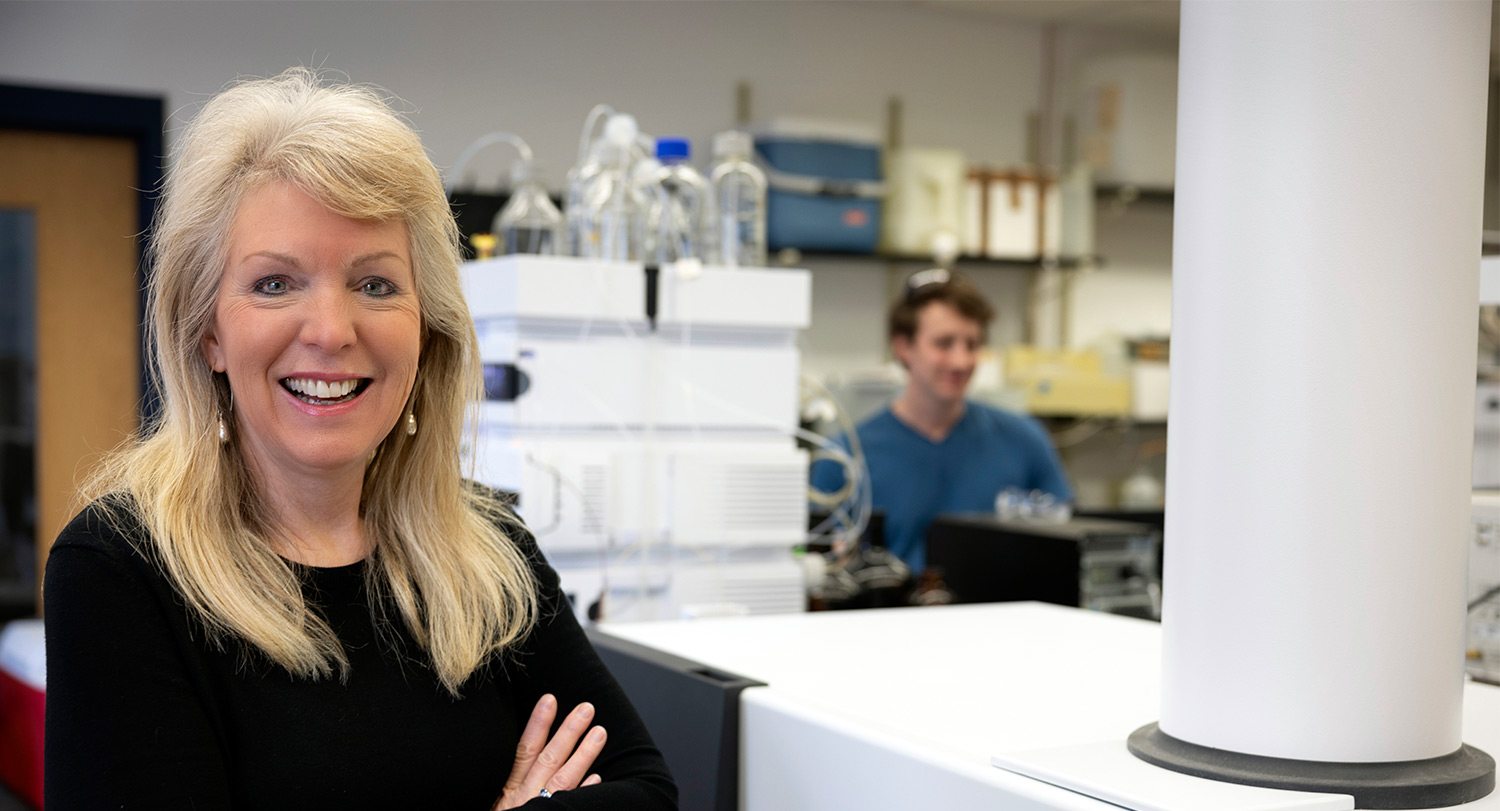 Susan Richardson smiles in lab with her arms crossed.