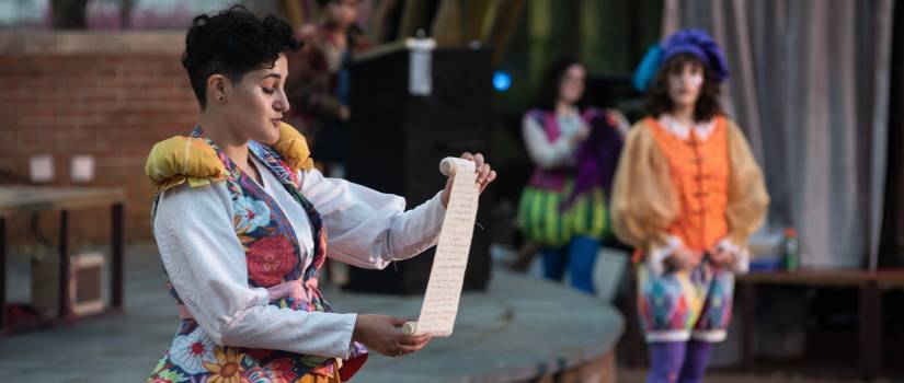 Shakespearian actor reading from a scroll.