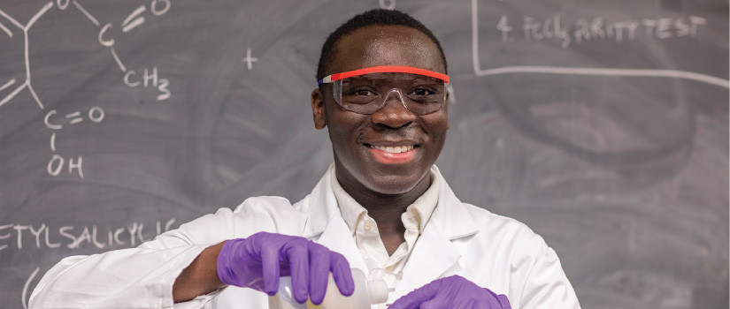 African American male student with lab coat in chemistry lab
