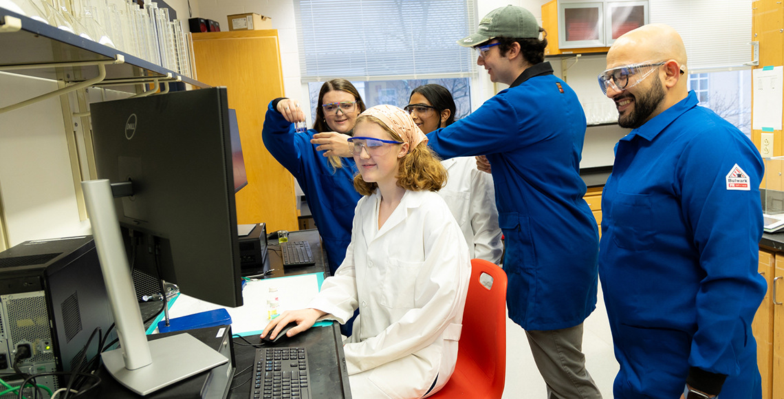 group of students in lab coats working on pc