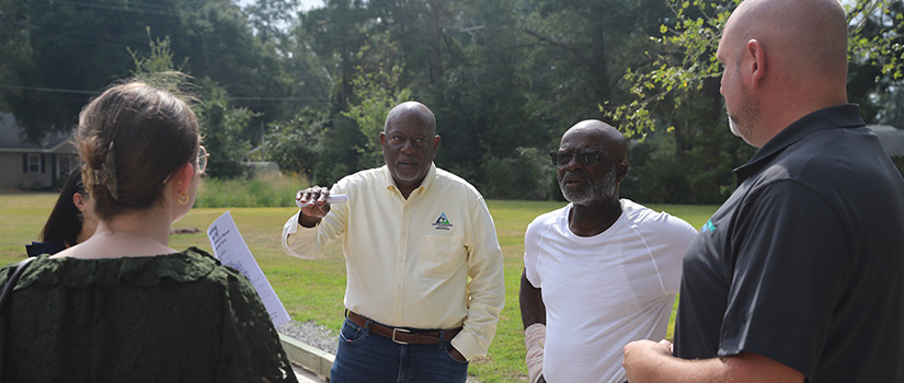 Ben Duncan speaks with a small group outdoors on a wooden walkway.