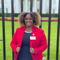 Jefferson stands in front of the White House lawn wearing a red blazer and black dress.