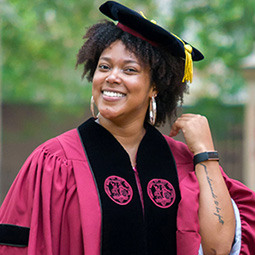 Photo of arfican american woman in graduation gear smiling. 