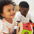 Photo of two toddlers learning with objects.
