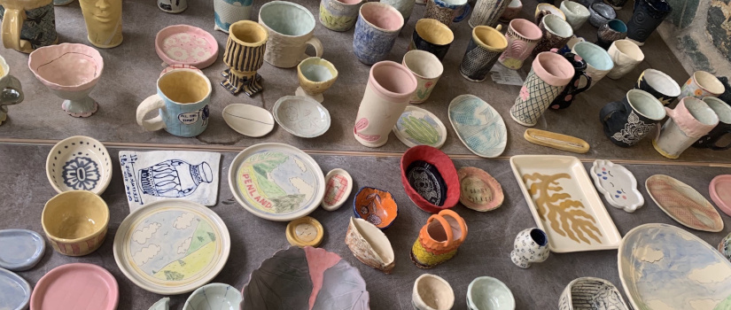 Multicolored pieces of glazed pottery are displayed against a grey table top.