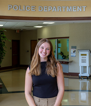 Claudia Case smiles in a headshot portrait taken inside a campus building. She has long light brown hair and is wearing a black sleeveless top.