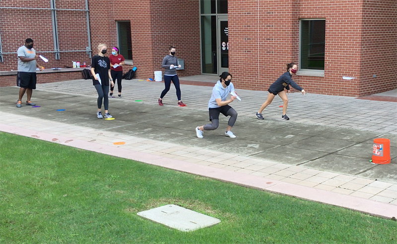 Students throw paper airplanes toward buckets