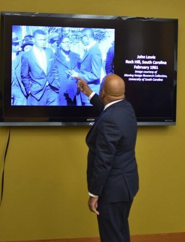 John Lewis points to an image of himself on a video screen