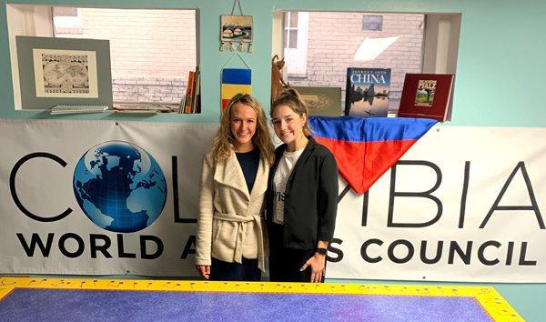 Lilly Kays and a fellow intern stand in front of a Columbia World Affairs Council sign.