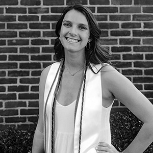 Black and white image of Kylie hurst in white graduation dress and cords