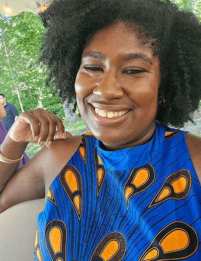 Yelana Sims, new history faculty member at USC, smiling outdoors in a blue patterned dress.
