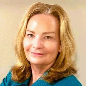 a woman smiling with a teal top on