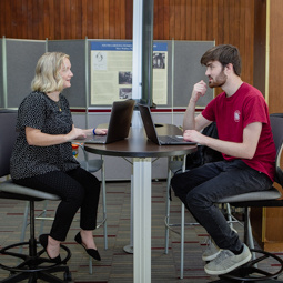 student talking to faculty member in library