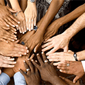 Hands of many races reach towards a the center of the frame.